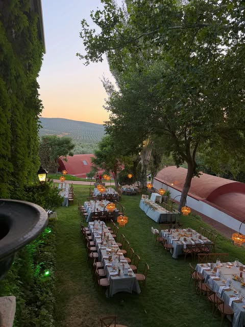 Mesas largas preparadas en el jardín del cortijo al atardecer
