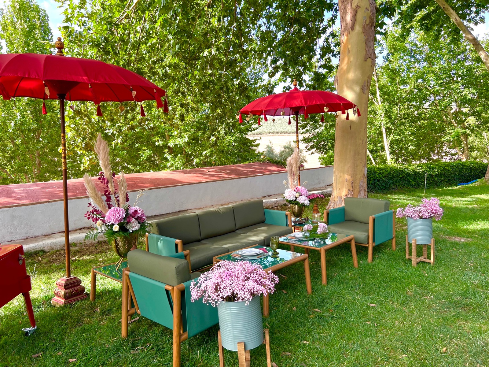 Zona chill-out en el jardín con sombrillas rojas y sofás